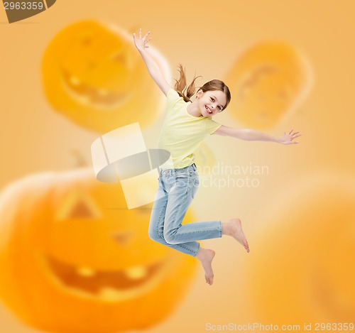 Image of smiling girl jumping over pumpkins background