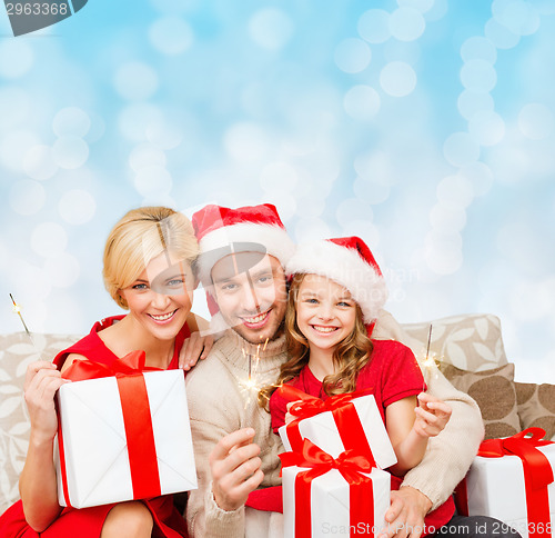 Image of happy family in santa helper hats with gift boxes