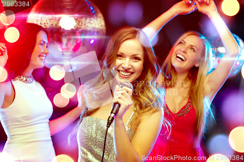 Image of three smiling women dancing and singing karaoke