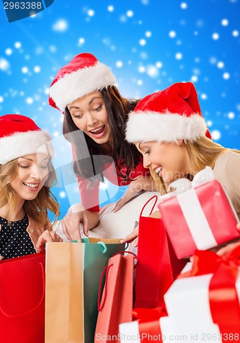 Image of smiling young women in santa hats with gifts