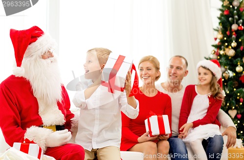 Image of smiling family with santa claus and gifts at home