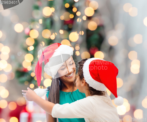 Image of happy mother and girl in santa hats