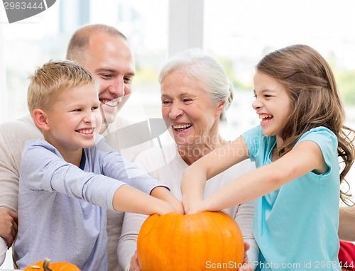 Image of happy family sitting with pumpkins at home