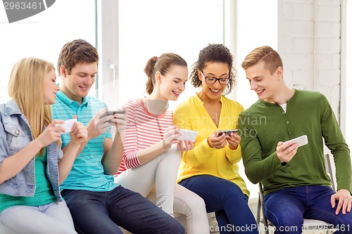 Image of smiling students with smartphone texting at school