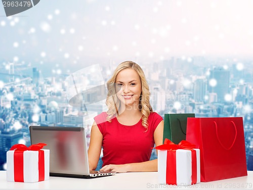 Image of smiling woman in red shirt with gifts and laptop