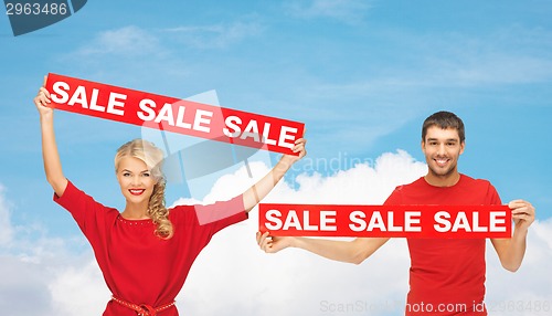Image of smiling man and woman with red sale signs