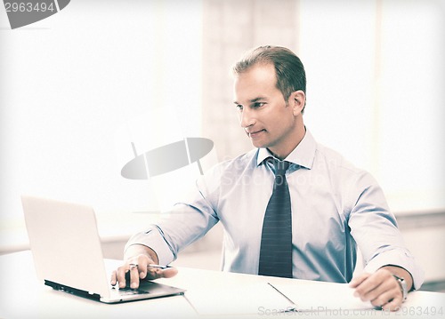 Image of miling businessman working in office