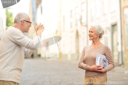 Image of senior couple photographing on city street