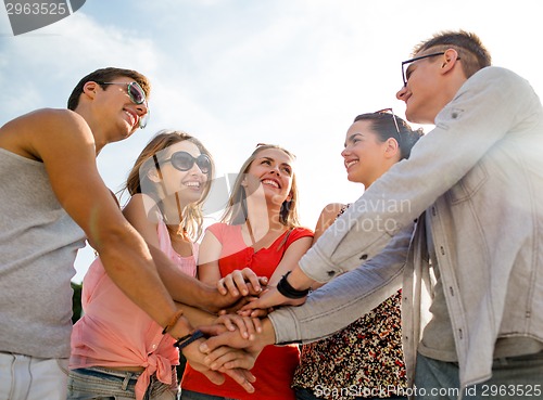 Image of group of smiling friends with hands on top in city