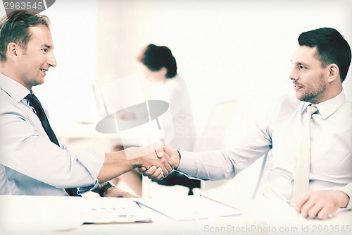 Image of businessmen shaking hands in office