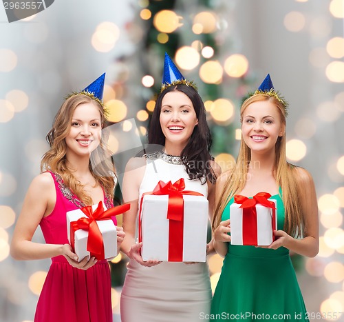 Image of smiling women in party caps with gift boxes