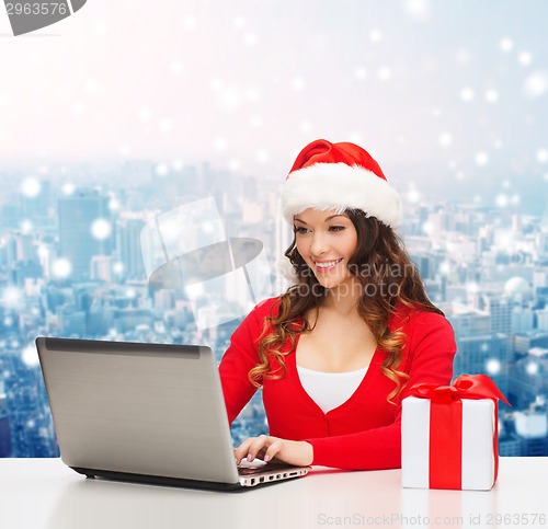 Image of smiling woman with gift box and laptop