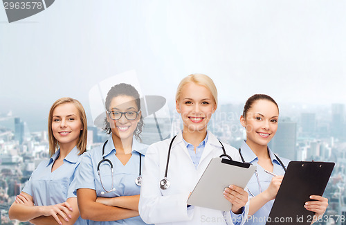 Image of smiling female doctor and nurses with tablet pc