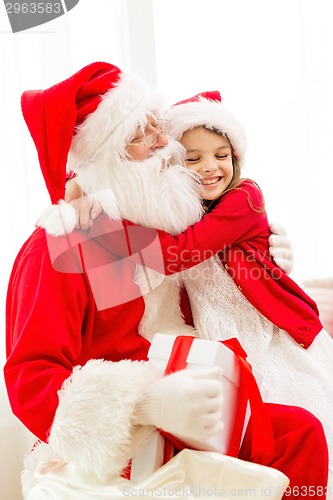 Image of smiling girl with santa claus and gift at home