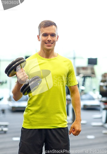 Image of smiling man with dumbbell in gym