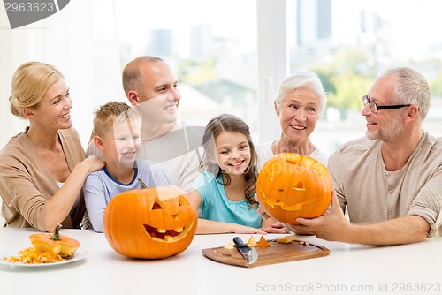 Image of happy family sitting with pumpkins at home