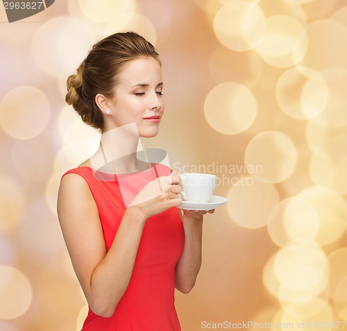 Image of smiling woman in red dress with cup of coffee