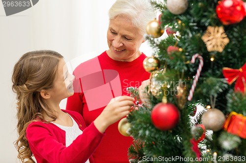 Image of smiling family decorating christmas tree at home