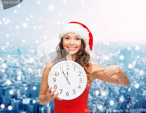 Image of smiling woman in santa helper hat with clock