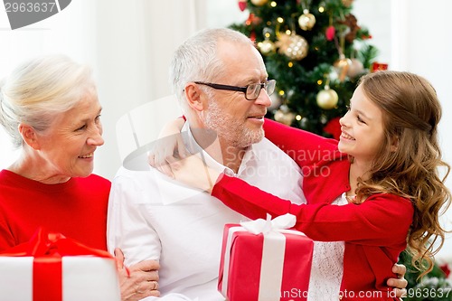 Image of smiling family with gifts at home