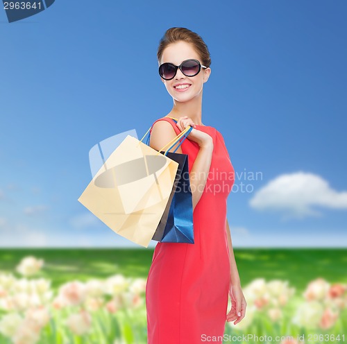 Image of smiling woman in red dress with shopping bags