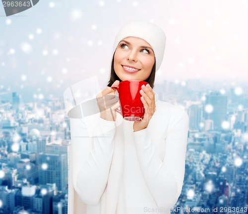 Image of smiling young woman in winter clothes with cup