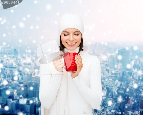 Image of smiling young woman in winter clothes with cup