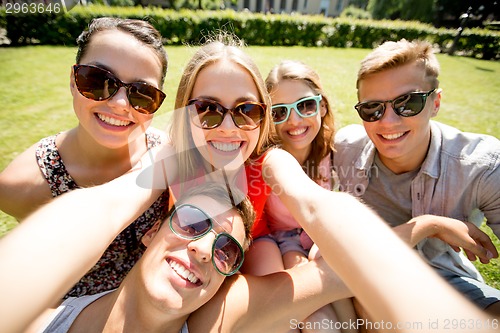 Image of group of smiling friends making selfie in park