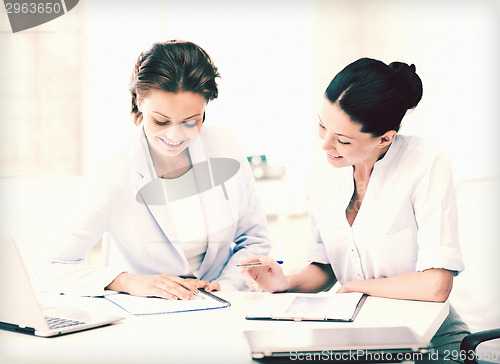 Image of two smiling businesswomen working in office
