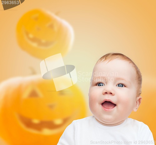 Image of smiling baby over pumpkins background