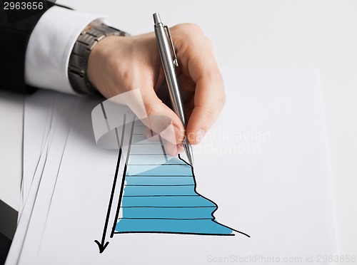 Image of close up of male hand with pen drawing graph
