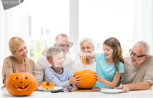 Image of happy family sitting with pumpkins at home