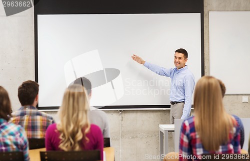 Image of group of students and smiling teacher in classroom