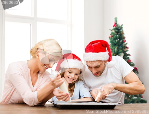 Image of happy family in santa helper hats cooking