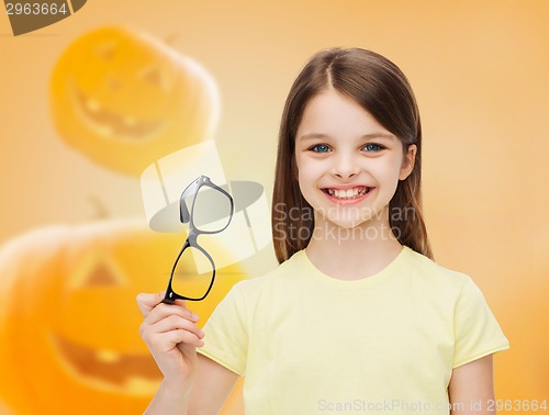Image of smiling girl in glasses over pumpkins background