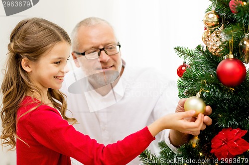 Image of smiling family decorating christmas tree at home