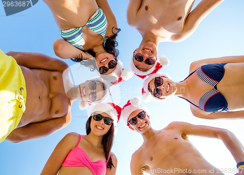 Image of smiling friends in circle on summer beach