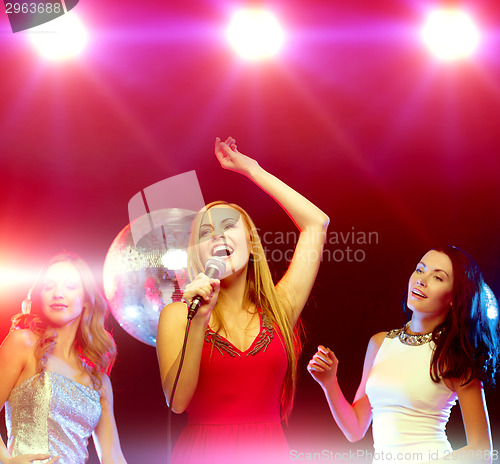 Image of three smiling women dancing and singing karaoke