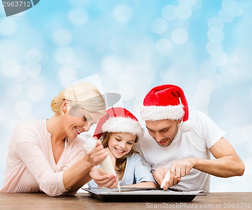 Image of happy family in santa helper hats cooking