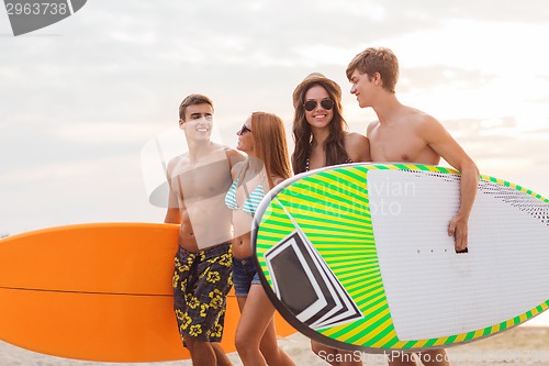 Image of smiling friends in sunglasses with surfs on beach