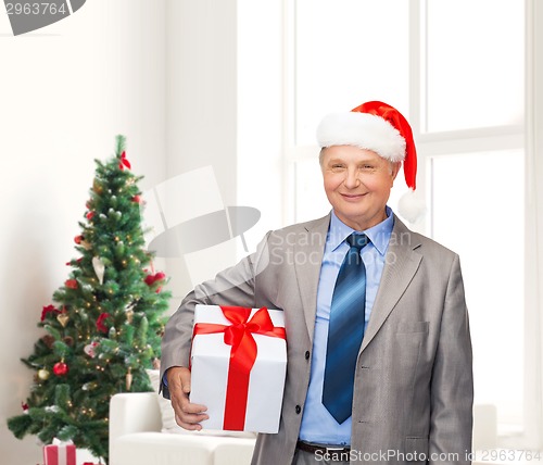 Image of smiling man in suit and santa helper hat with gift