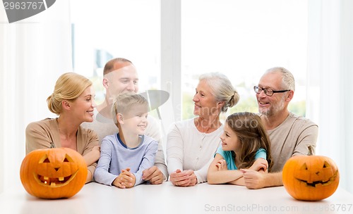 Image of happy family sitting with pumpkins at home