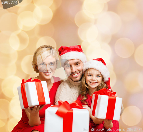 Image of happy family in santa helper hats with gift boxes