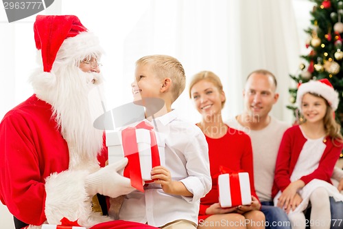 Image of smiling family with santa claus and gifts at home