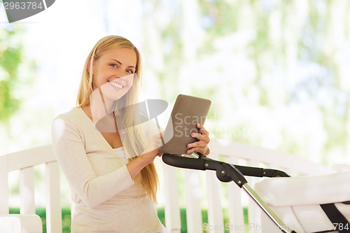 Image of happy mother with tablet pc and stroller in park