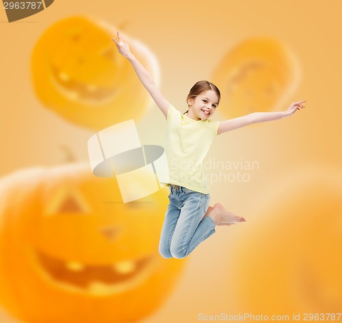 Image of smiling girl jumping over pumpkins background