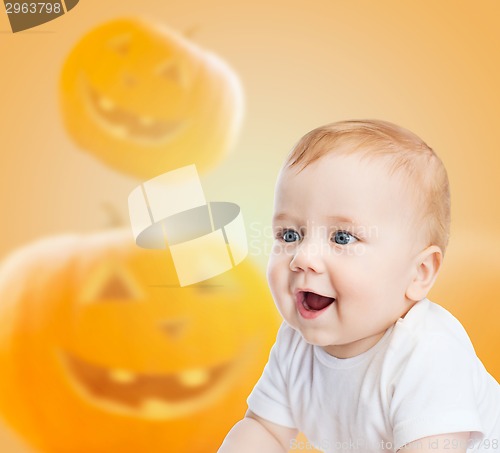 Image of smiling baby over pumpkins background