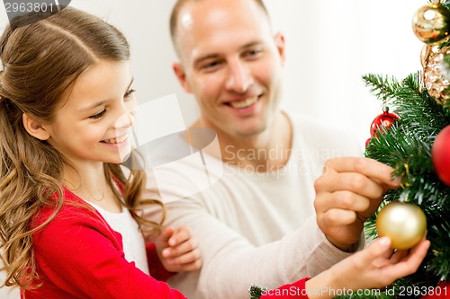 Image of smiling family decorating christmas tree at home