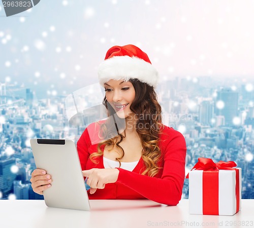 Image of smiling woman in santa hat with gift and tablet pc