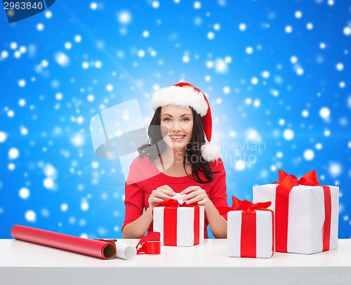 Image of smiling woman in santa helper hat packing gifts